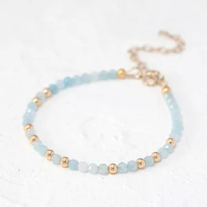 Detail of beaded bracelet with sky blue natural stones and golden metal accents