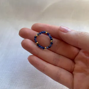 Detail of handcrafted blue faceted beads and gold spacers on a flexible beaded ring