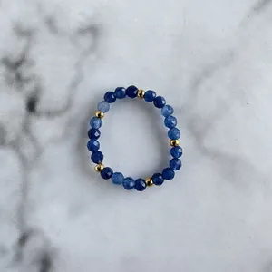 Detailed macro view of handmade beaded ring with blue faceted natural stones and gold beads