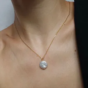 Detail shot of a simple 18k gold plated necklace with a natural freshwater pearl on skin