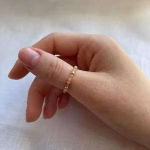 Close-up of minimalist handmade ring with natural faceted stones and gold metal beads