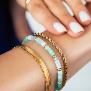 Primer plano del set de pulseras de tres capas con cadena dorada y cuentas de piedra