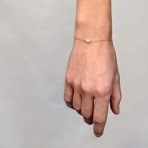 Macro detail of 18k gold plated titanium chain with a natural freshwater pearl on wrist