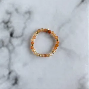 Macro detail of handmade beaded ring with orange natural stones and gold metal spacers
