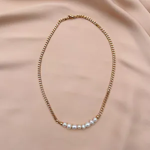 Close-up of 18k gold-plated curb chain with eight white baroque pearls on pink silk
