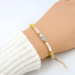 Detalle de una pulsera de cuentas de piedra de colores con espaciadores dorados al pulso