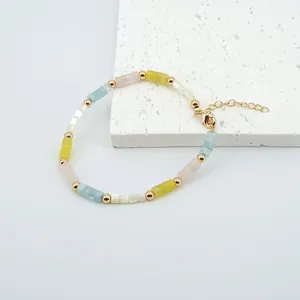 Detalle de pulsera de cuentas de piedra de colores con espaciadores dorados y cierre ajustable