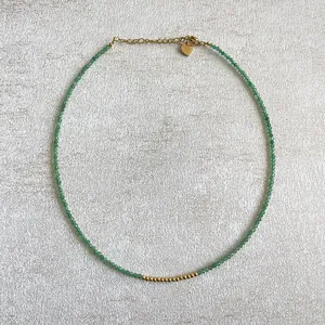 Gros plan du collier en perles de pierre verte avec accents dorés et pendentif en cœur