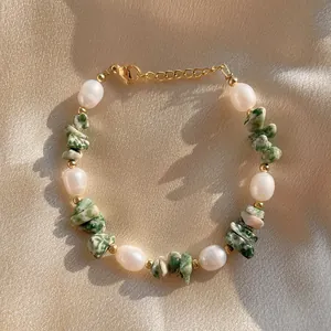 Détail de bracelet en perles d'eau douce avec pierres naturelles vertes et fermoir doré