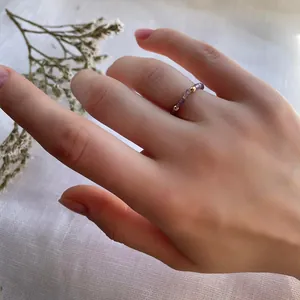 Detail of handcrafted purple beads and gold bead ring worn on hand with linen background