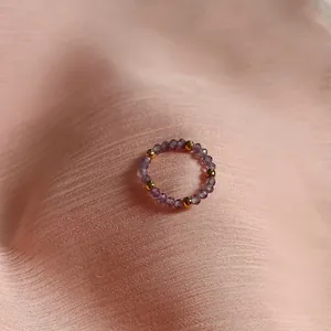 Macro shot of handmade beaded ring with purple faceted stones and gold metal spacers