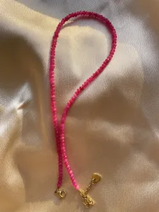 Detail of fuchsia beaded necklace with 18k gold plated steel clasp on silk fabric