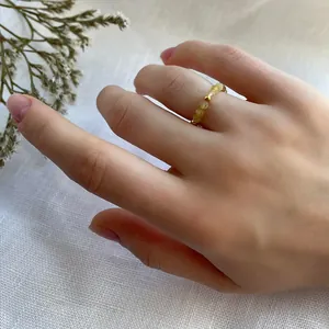 Detail of handmade beaded ring with yellow natural stones and gold spacer beads on linen
