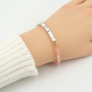 Detalle de pulsera de cuentas con mármol y piedras rosas en la muñeca con toques dorados