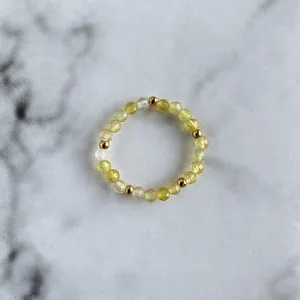Detail of yellow faceted beads and golden accents on a handmade beaded elastic ring