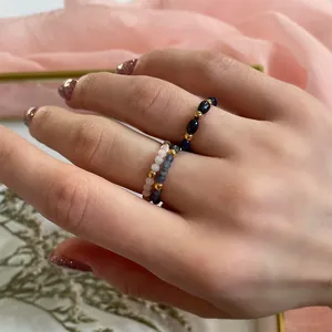 Close-up of stacked handmade beaded rings with semi-precious stones and gold spacers