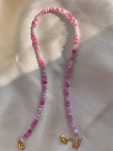 Detailed view of pink and purple natural stone beads with gold lobster clasp and logo tag