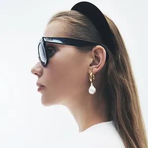 Vue détaillée d'une boucle d'oreille dorée avec une perle baroque sur un mannequin femme