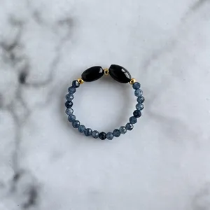 Macro shot of handmade beaded ring with faceted blue stones and golden metal spacers