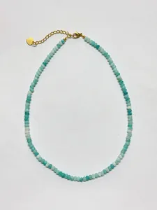 Detailed view of faceted blue beads necklace with gold lobster clasp and heart pendant