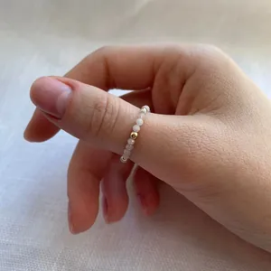 Close-up of handmade beaded ring with translucent stones and small gold metal beads