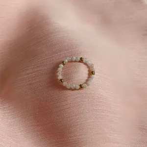 Detail of handmade beaded ring with pink stones and golden beads on silk fabric