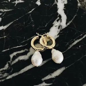 Détail macro de boucles d'oreilles anneaux dorés avec perles baroques et poinçon S925
