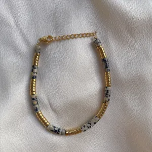 Detail of Dalmatian Jasper beads and 18k gold plated stainless steel on silk background