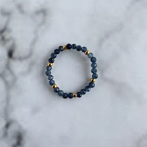 Detail of blue faceted natural stone beads and gold metal spacers on a beaded ring