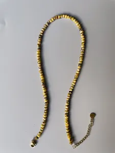 Detail of yellow faceted natural stone beads with gold plated lobster clasp and chain