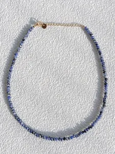 Detailed macro view of faceted blue natural stone beads with gold plated lobster clasp