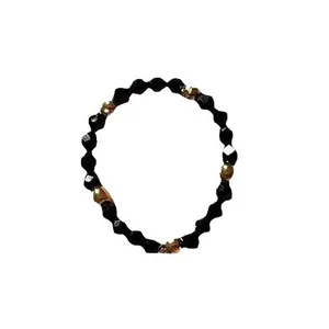 Handmade beaded ring featuring faceted black stones and gold-tone accents on white background