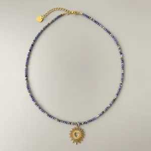 Detalle macro del collar de cuentas naturales con colgante de sol y cierre de corazón