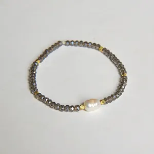 Détail du bracelet en perles avec cristaux gris facettés et perle baroque centrale