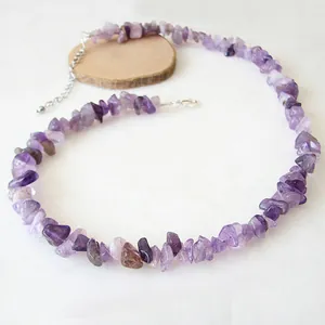 Détail d'un collier en pierres concassées violettes avec fermoir argenté sur bois