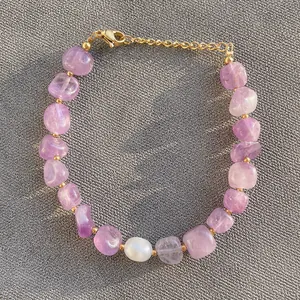 Détail macro du bracelet en améthyste avec perle baroque et fermoir mousqueton doré