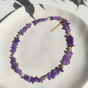Gros plan d'un collier bohème avec éclats d'améthyste violette et perles baroques sur plat