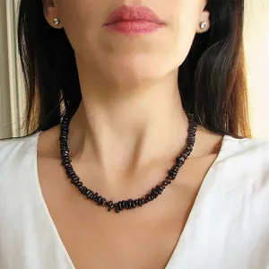 Détail du collier de pierres naturelles rouge foncé porté par un mannequin en vacances
