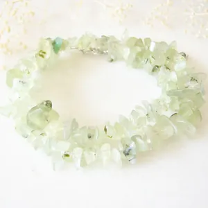 Détail du collier de pierres naturelles vert clair sur fond de pierre blanche