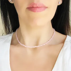 Dettaglio di un girocollo in pietra naturale rosa sfaccettata su una modella elegante