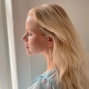 Gros plan de boucles d'oreilles créoles dorées avec perles d'eau douce sur un modèle