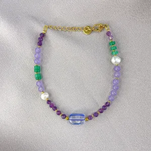 Macro shot of colorful beads, irregular pearls, and gold-plated lobster clasp on silk