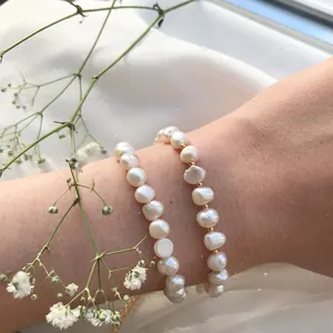 Détail d'un bracelet en perles baroques avec billes dorées sur fond de soie blanche
