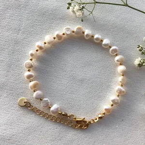 Détail d'un bracelet en perles d'eau douce avec perles dorées et fermoir mousqueton