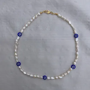 Detail of baroque pearl necklace with blue evil eye beads and golden lobster clasp