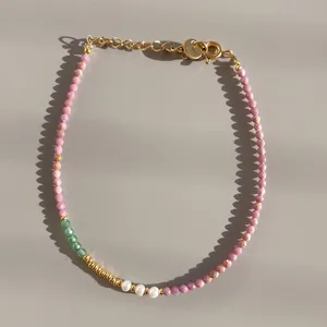 Détail de bracelet fait main avec pierres roses, perles vertes et perles d'eau douce