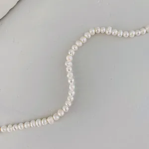 Dettaglio della collana di perle naturali d'acqua dolce bianco crema su fondo grigio
