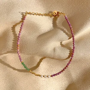 Détail d'un bracelet fait main avec pierres violettes, perles et fermoir doré