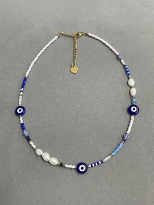 Detail of beaded evil eye necklace with baroque pearls and golden heart pendant