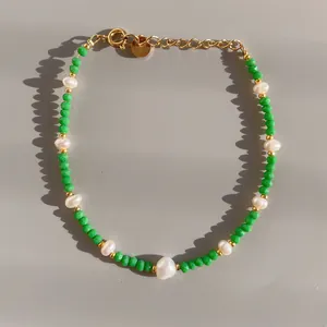 Gros plan de perles de cristal vert facetté et perles d'eau douce sur chaîne dorée